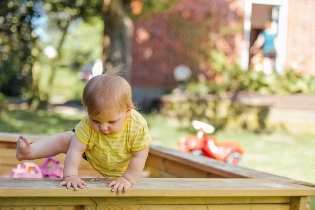 A toddler enjoying a fun outdoor photo session in a sandbox.
