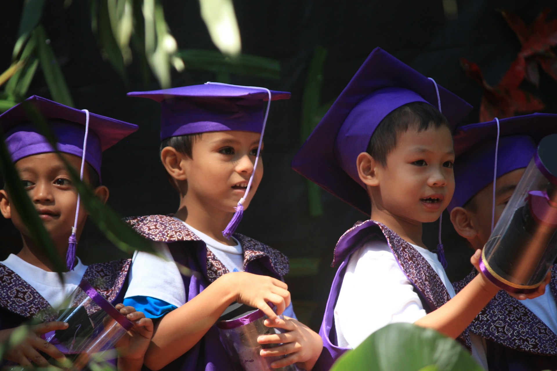 Graduate smiling proudly in cap and gown during a school portrait on graduation day in school.