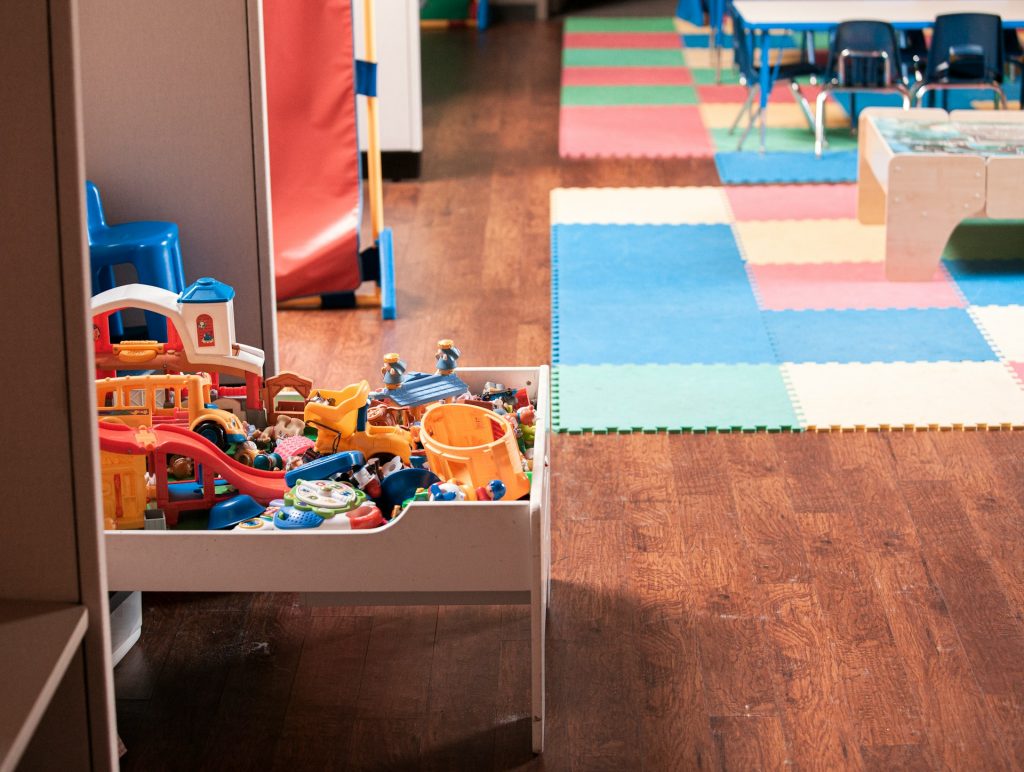 A toy rack on a colourful classroom playmat captured by a child care photographer Sydney.